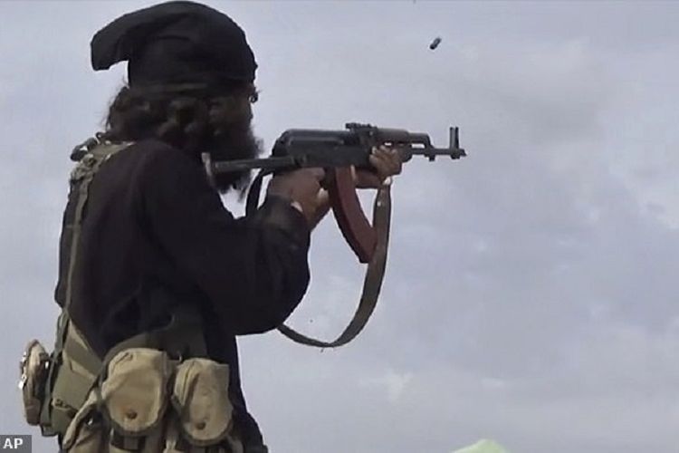 Seorang anggota Negara Islam Irak dan Suriah (ISIS) tengah menembakkan senapan AK-47.