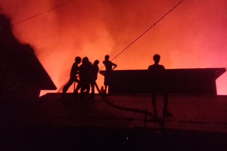 Petugas pemadam kebakaran harus naik ke atap rumah saat berusaha memadamkan api yang membakar 56 rumah di Alalak Selatan, Banjarmasin, Kalsel, Selasa (10/9/2019).