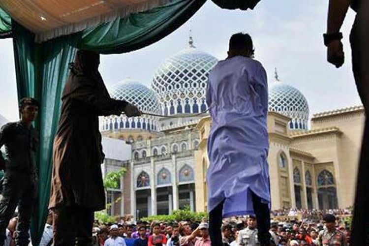 Seorang terhukum cambuk menjalani eksekusi cambuk di halaman Masjid Islamic Center, Kota Lhokseumawe, Jumat (23/3/2018).