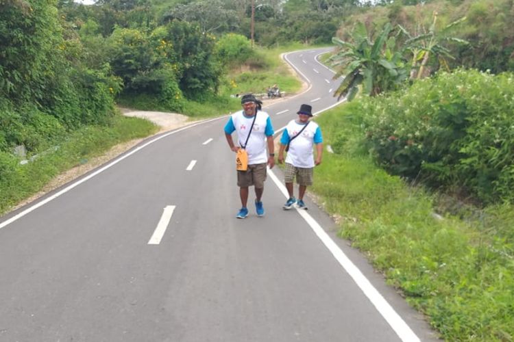 Togu Simorangkir dan Biston Hutahuruk ketika melewati tanjakan terjal dalam aksi jalan kaki memutari Danau Toba di hari ke empat, Kamis (22/11/2018).