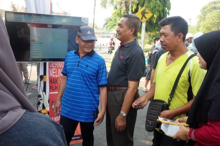 Sejumlah warga didampingi ketua KPU Jombang, Muhaimin Shofi (baju hitam), melakukan pengecekan Daftar Pemilih Tetap (DPT) Pemilu 2019, di area car free day di Jalan KH. Wahid Hasyim Jombang, Sabtu (28/10/2018) pagi.