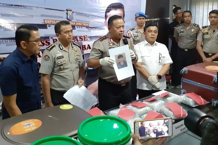 Polisi menunjukkan foto dan barang bukti sabu yang disimpan dalam galon cat di Mapolda Jatim, Selasa (9/7/2019)
