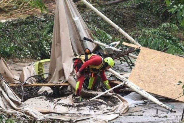 Tim penyelamat berdiri di tenda yang rusak di area perkemahan yang tersapu banjir pada Kamis (9/8/2018) di Saint-Julien-de-Peyrolas, Prancis selatan. (AFP/Boris Horvat)