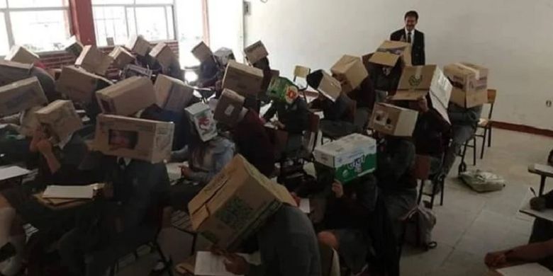 Foto yang viral ini memperlihatkan seorang guru di Meksiko mengawasi pelaksanaan ujian dengan para muridnya mengenakan kotak kardus demi menghindari menyontek.