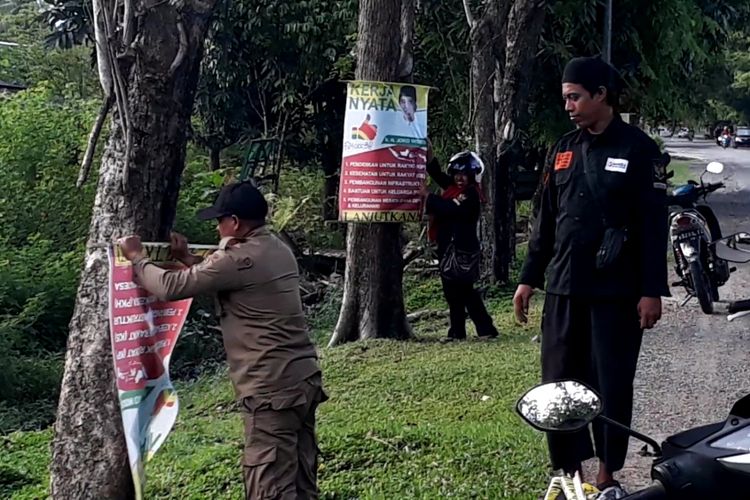 Satpol PP dan Bawaslu Palopo menertibkan APK yang menempel dan di paku di pohon, APK tersebut terpasang di sepenjang ruas jalan di kecamatan Wara Selatan, Sabtu (02/03/2019)