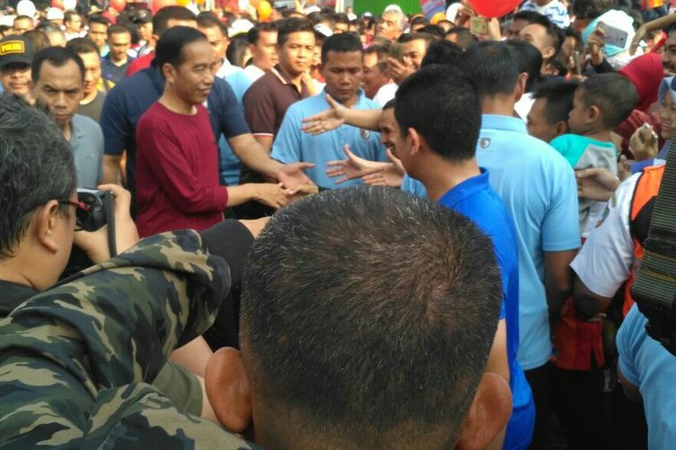 Presiden Jokowi memakai kaus lengan panjang merah menyapa warga Solo di CFD, Minggu (1/4/2018).