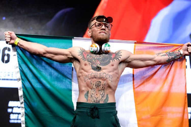 Conor McGregor hadir dengan bendera Irlandia pada acara timbang badan jelang duel melawan Floyd Mayweather, Jumat (25/8/2017). 