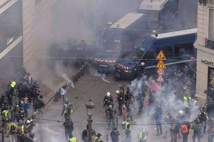 Polisi anti huru-hara Perancis memblokade para anggota massa gilets jaunes (Rompi Kuning) dengan gas air mata terlihat di Champs-Elysees, Paris, Perancis, pada 8 Desember 2018.