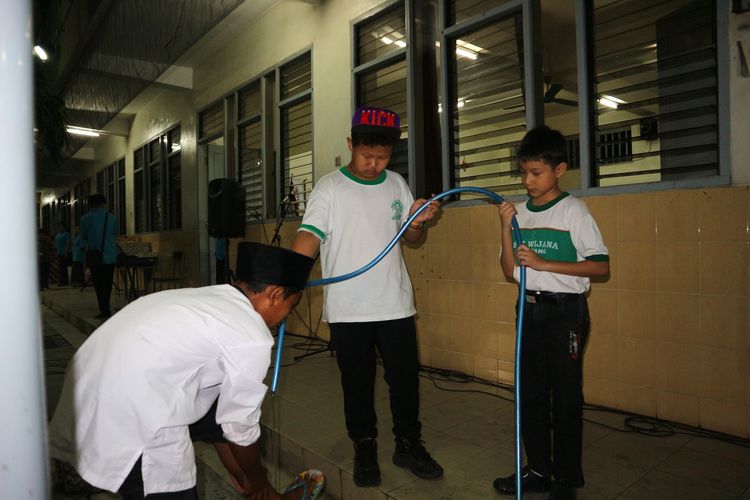 Siswa SD Kristen Petra Jombang membantu salah satu siswa MI Islamiyah berwudlu sebelum menggelar shalat Maghrib di komplek SD Kristen Petra Jombang, (27/5/2019) malam.                         