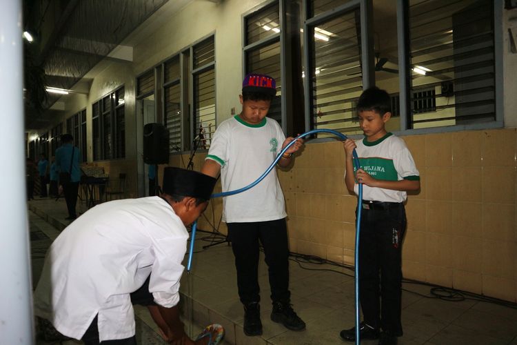 Siswa SD Kristen Petra Jombang membantu salah satu siswa MI Islamiyah berwudlu sebelum menggelar shalat Maghrib di komplek SD Kristen Petra Jombang, (27/5/2019) malam.