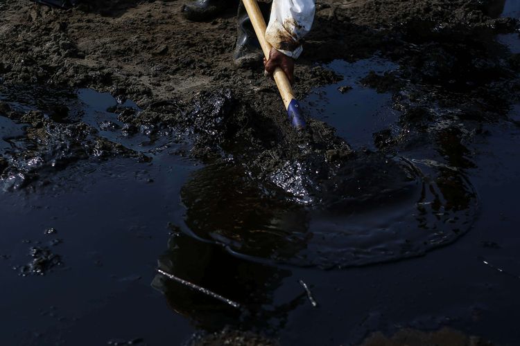 Warga mengumpulkan limbah tumpahan minyak Oil Spill yang tercecer milik Pertamina di Pesisir Pantai Cemarajaya, Karawang, Jawa Barat, Minggu (4/8/2019). Pasir yang tercemar minyak tersebut dikumpulkan dan akan dipindahkan ke pabrik penyimpanan limbah B3 (Bahan Berbahaya dan Beracun) untuk dimusnahkan.