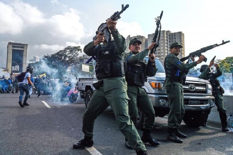 Anggota dari Garda Nasional Bolivarian yang memilih mendukung oposisi Venezuela pimpinan Juan Guaido membalas tembakan pasukan loyalis Presiden Nicolas Maduro dalam ketegangan yang terjadi  di Caracas, Selasa (30/4/2019).