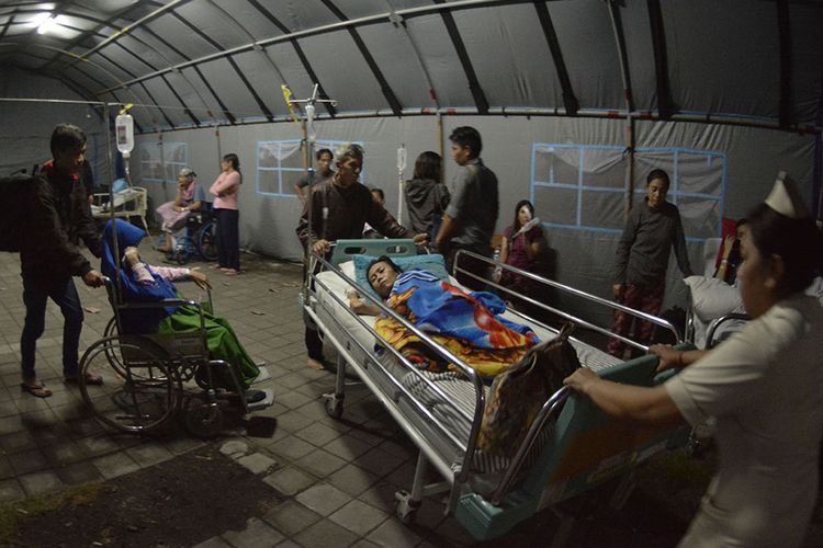 Petugas medis memindahkan pasien dari ruang perawatan ke tenda usai terjadi gempa di RSUP Sanglah, Denpasar, Bali, Minggu (19/8/2018). Sejumlah pasien di rumah sakit tersebut dipindahkan ke tenda dan lorong rumah sakit pascagempa bermagnitudo 7 yang berpusat di Lombok Timur pada Minggu malam.