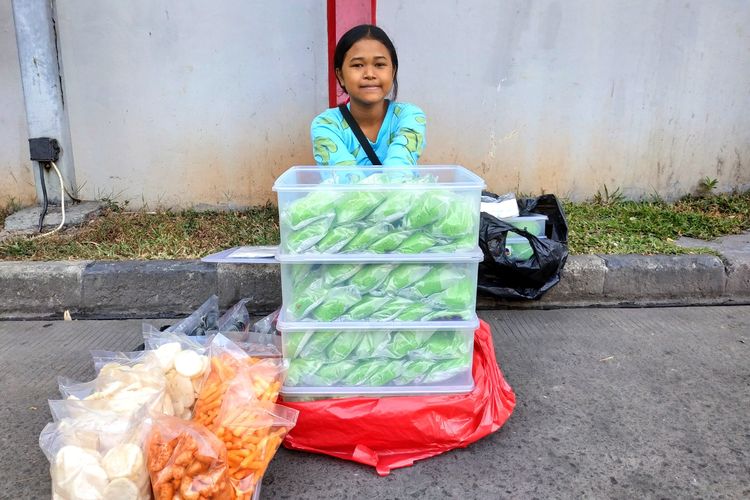 Dewi Febriyanti (13) ketika berjualan bakpau di Pom Bensin sebelah perumahan Ubud Village, Tangerang pada Rabu (24/7/2019).