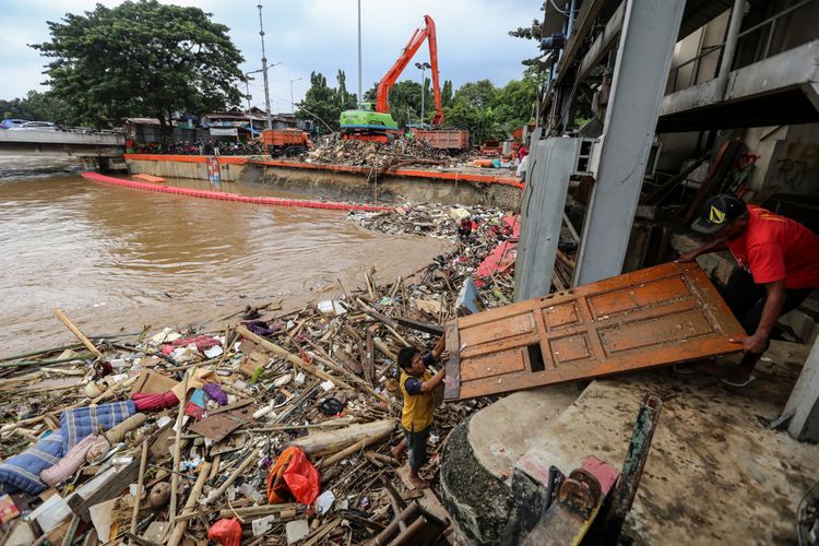 Warga menggambil pintu rumah yang terbawa arus di Pintu Air Manggarai, Jakarta, Rabu (7/2/2018). Dinas Lingkungan Hidup dan Kebersihan DKI Jakarta telah mengangkut 1.596 ton sampah yang hanyut akibat air kiriman dari Bendungan Katulampa, Bogor pasca banjir yang melanda Jakarta.