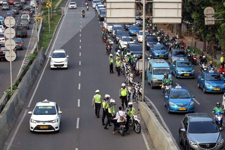 Polisi melakukan razia sepeda motor yang nekat menerobos ke jalan layang non tol (JLNT) Kampung Melayu-Tanah Abang, Jakarta, Selasa (25/7/2017). Pengendara motor masih nekat memasuki dan melintasi JLNT tersebut baik dari arah Tanah Abang maupun Kampung Melayu. KOMPAS IMAGES/KRISTIANTO PURNOMO