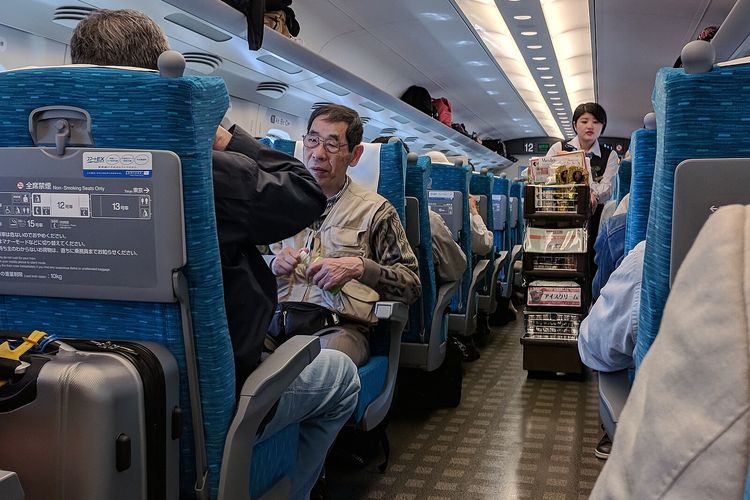 Seorang pramugari mendorong gerobak makanan ringan di lorong kereta Shinkansen selama perjalanan di dekat Odawara.