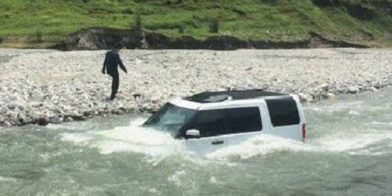 Seorang pria menunggu di tepi sungai seraya melihat mobilnya tergenang. Dia membawa mobil Land Rover-nya ke sungai untuk dibersihkan daripada menghamburkan uang ke tempat cuci mobil.