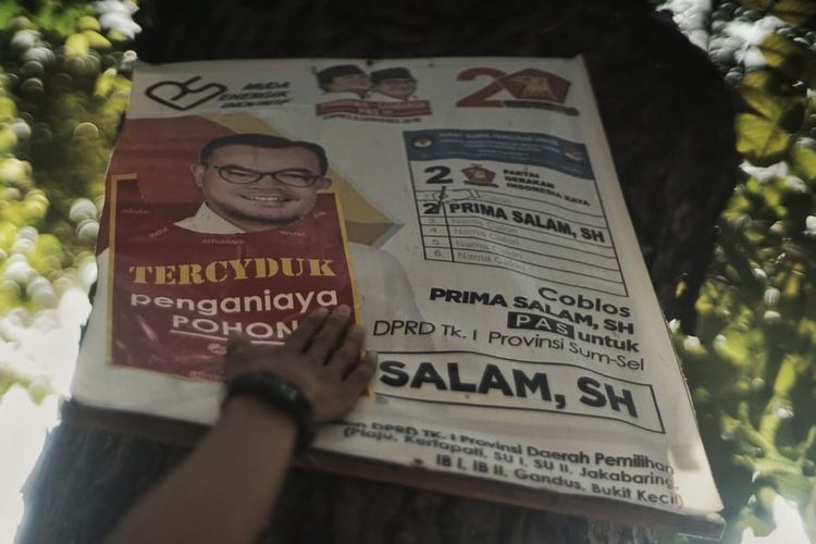 Pemasangan stiker sindiran oleh komunitas Turun Tangan Palembang kepada poster caleg yang terpasang dipohon dengan menggunakan paku.