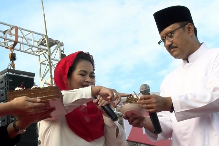 Gus Ipul memegang potongan kue ulang tahun Presiden Joko Widodo yang diberikan kepada kader Partai Gerindra dalam kampanye paslon Gus Ipul-Puti di Lapangan Gulun, Kota Madiun, Jawa Timur, Kamis (21/6/2018).