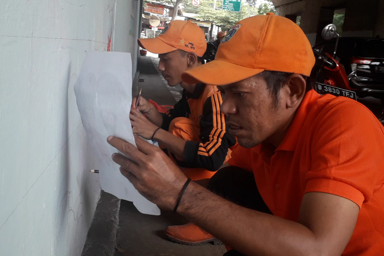 Rosyid, petugas PPSU Kelurahn Setu, tengah menggambar lukisan mural ondel-ondel di terowongan Jalan Setu Raya, Rabu (19/6/2019).