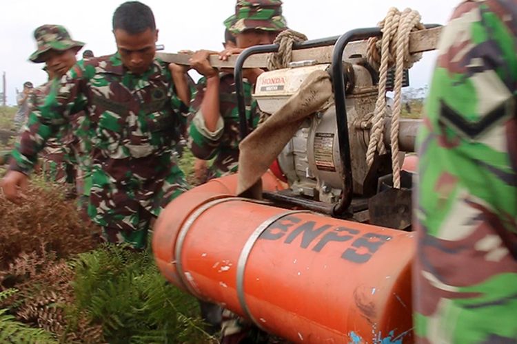 Prajurit TNI menggotong mesin pompa air saat menuju lokasi titik api yangberada ditengah hutan gambut kawasan Desa Lapang, Kecamatan Johan Pahlawan, Kabupaten Aceh Barat, Minggu (27/8/17).