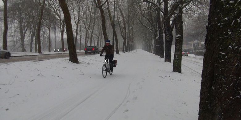 Bersepeda di tengah salju yang menyelimuti kota Brussel, Belgia, Jumat (2/3/2018). Ketebalan salju sekitar 10 cm dengan empasan angin dingin.
