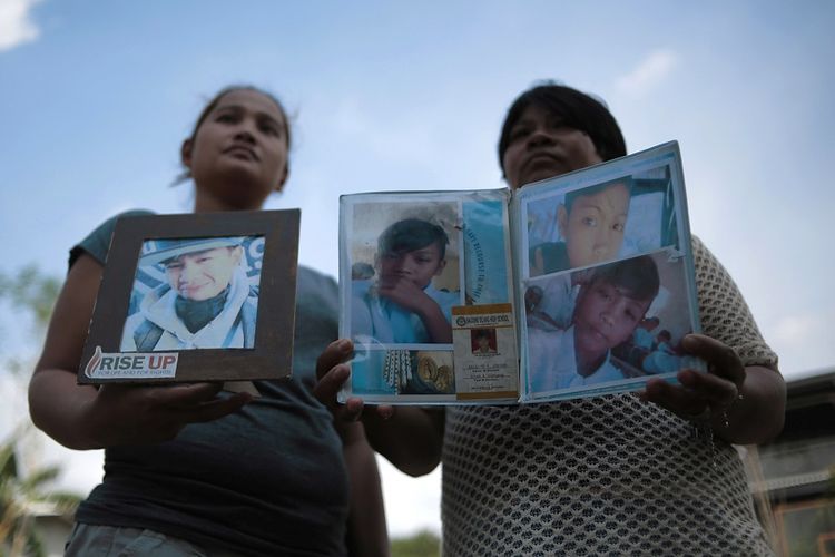 Dua warga Filipina membawa foto anak-anak yang turut menjadi korban dalam perang melawan narkoba yang digalakkan pemerintah Filipina.