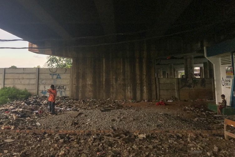 Dua anak bermain di sekitar sampah yang berserakan di kolong Tol Wiyoto Wiyono, Kelurahan Papango, Jakarta Utara, Kamis (11/4/2019).