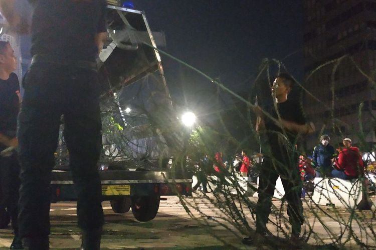 Anggota Brimob menggeret barikade kawat berduri yang rusak di depan Sarinah, Kamis (23/5/2019) malam.