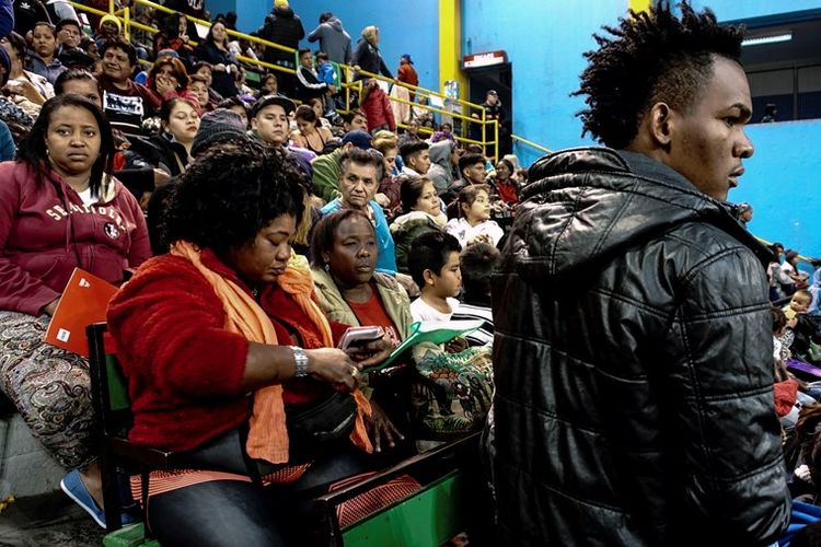 Para migran mengantre untuk mengurus izin tinggal mereka kepada otoritas migrasi di Stadion Victor Jara, Santiago, Chile.