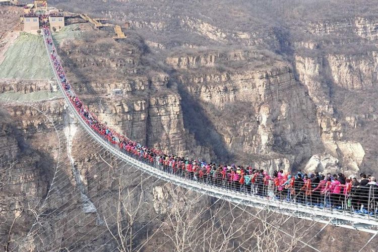 Ratusan orang berjalan di atas jembatan kaca Hongyagu secara bersamaan untuk menguji kekuatan jembatan tersebut, Selasa (20/3/2018).
