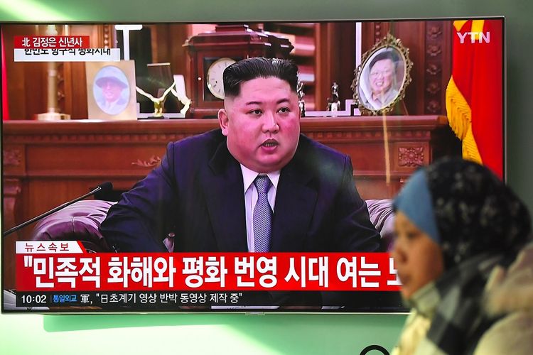 Seorang perempuan melintas di depan televisi yang menayangkan pidato Tahun Baru Pemimpin Korea Utara Kim Jong Un (1/1/2019).