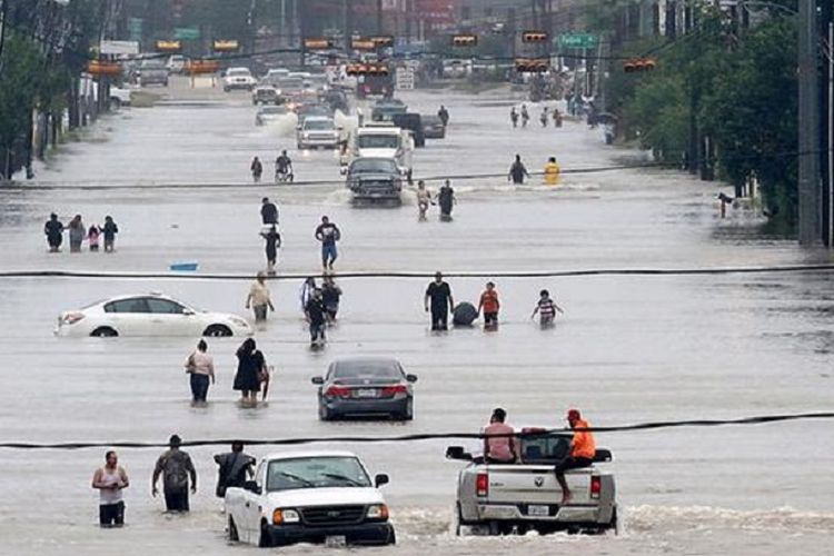 Warga berjalan di tengah banjir yang menggenangi jalan raya Telephone di kota Houston, Amerika Serikat, Minggu (27/8/2017) waktu setempa.