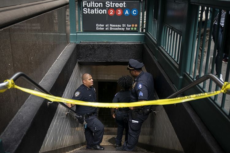 Petugas kepolisian berjaga di depan pintu masuk stasiun kereta bawah tanah di Fulton Street, New York, yang ditutup setelah adanya laporan temuan paket misterius, Jumat (16/8/2019).