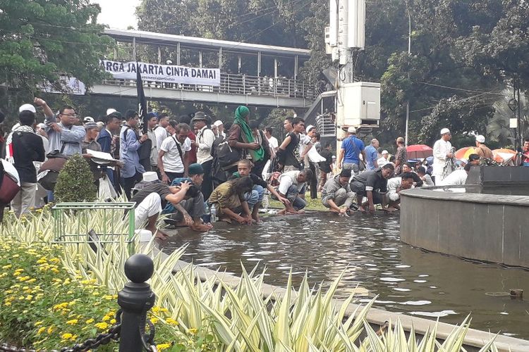 Massa aksi mengambil wudhu di kolam air mancur Patung Arjuna Wiwaha atau Patung Kuda, Kamis (27/6/2019) sore.