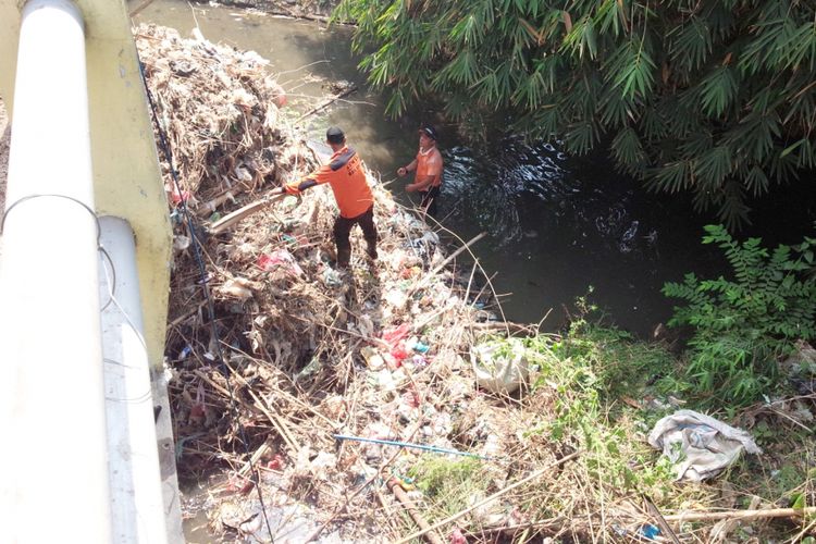 Para relawan membersihkan sampah yang menumpuk di bawah jembatan Kali Putih di Desa Selorejo, Kecamatan Mojowarno, Kabupaten Jombang, Minggu (04/11/2018).
