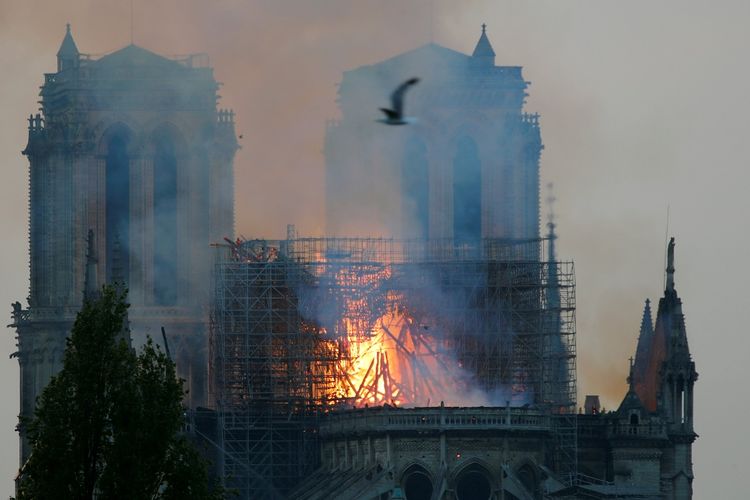 Asap membubung dari Gereja Notre Dame yang terbakar pada Senin (15/4/2019) di Paris, Perancis.