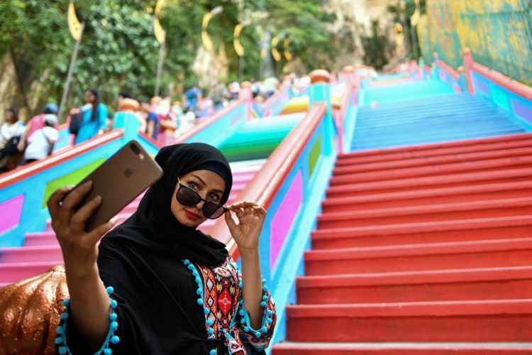 A woman takes selfies in front of the newly-painted 272-steps staircase leading to Malaysias Batu Caves Hindu temple in Kuala Lumpur on August 30, 2018. (Photo by Manan VATSYAYANA / AFP)        (Photo credit should read MANAN VATSYAYANA/AFP/Getty Images)