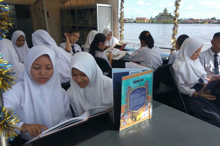 Sejumlah siswa terlihat membaca buku di perpustakaan apung usai peresmian di pelabuhan Seng Hie, Pontianak, Kalimantan Barat (5/12/2017)