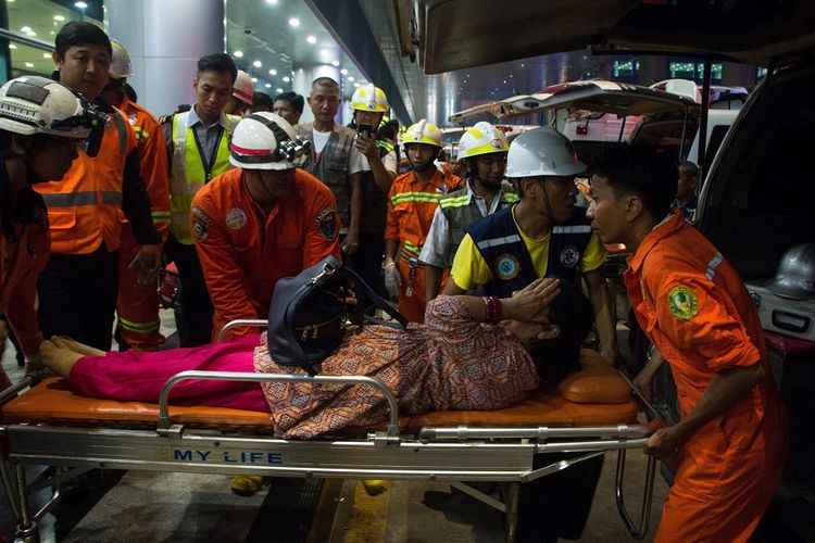 Petugas medis membawa salah seorang perempuan penumpang pesawat yang tergelincir di landasan pacu di Bandara Yangon, Myanmar, Rabu (8/5/2019).