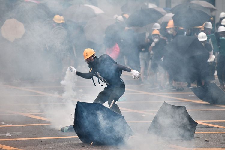 Pengunjuk rasa melemparkan kembali kaleng gas air mata yang ditembakkan polisi anti-huru hara dalam aksi protes di Yuen Long, Hong Kong, Sabtu (27/7/2019).