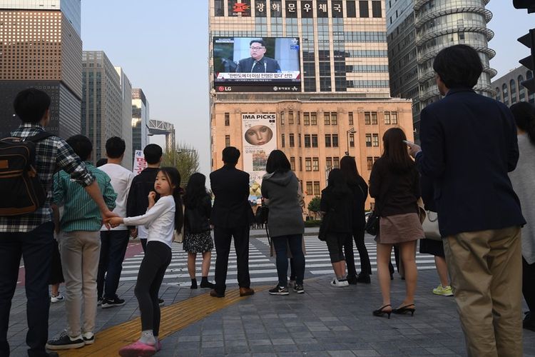 Pejalan kaki menyaksikan berita KTT Antar-Korea di televisi, Jumat (27/4/2018).