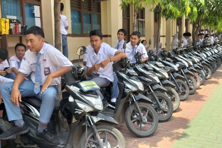 Sejumlah siswa SMA Negeri 4 Tangerang Selatan berkumpul dekat barisan motor yang telah dirapikan oleh satpam sekolah itu, Slamet Gunaedi, Senin (4/2/2019). Satpam tersebut merapikan motor para siswa berdasarkan merek dan warnanya.