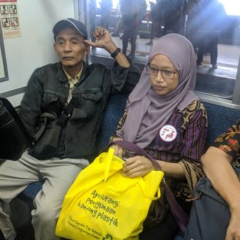 Seorang wanita yang mengenakan pin khusus ibu hamil di KRL diberi tempat duduk oleh penumpang lain.