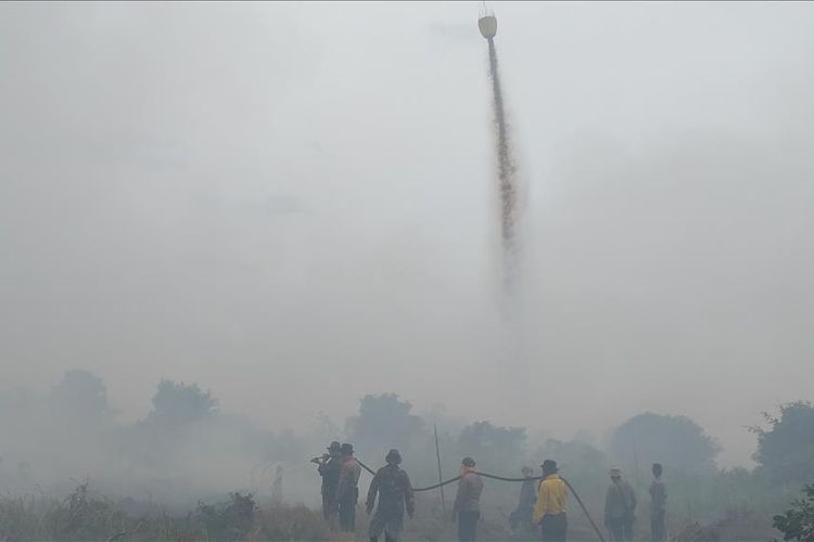 Petugas kepolisian dan TNI berupaya memadamkan api karhutla dalam kondisi penuh asap di Desa Teluk Bano II, Kecamatan Pekaitan, Kabupaten Rohil, Riau, Rabu (3/7/2019). Pemadaman juga dibantu dua unit helikopter BNPB. 