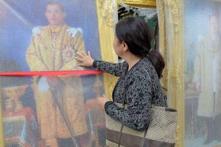 Salah seorang warga Thailand mengamati foto keluarga kerajaan.