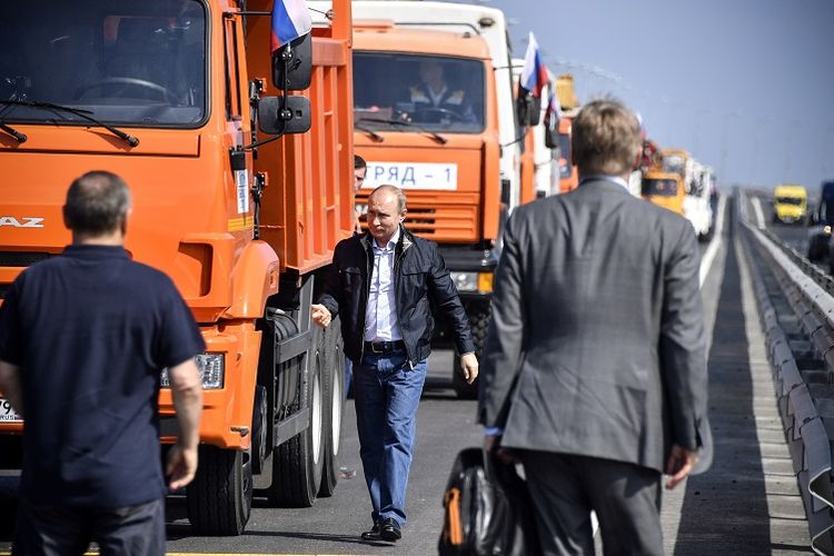 Presiden Rusia Vladimir Putin bersiap mengemudikan truk untuk melintasi jembatan baru sepanjang 19 kilometres yang terbentang di atas Selat Kerch Strait yang menghubungkan wilayah selatan Rusia dengan Semenanjung Crimea, Selasa (15/5/2018). 