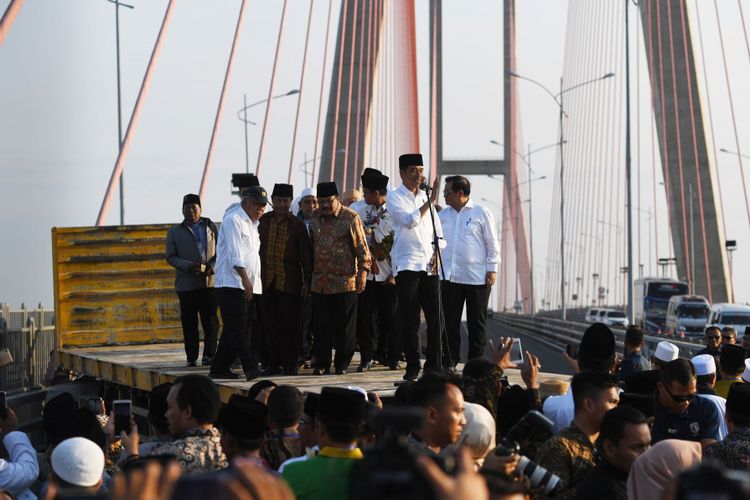 Presiden Joko Widodo (kedua kanan) didampingi Menteri PUPR Basuki Hadimuljono (kedua kiri) dan Sekretaris Kabinet Pramono Anung (kanan) serta pejabat setempat dan para ulama berada diatas truk saat meresmikan pembebasan tarif tol Jembatan Suramadu di Surabaya, Jawa Timur, Sabtu (27/10/2018). Pembebasan tarif tol tersebut diharapkan berdampak pada pertumbuhan ekonomi di Pulau Madura.