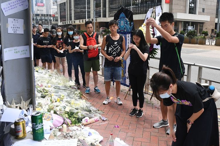 Para pelayat mengantre untuk memberikan penghormatan terakhir di lokasi jatuhnya salah seorang pengunjuk rasa menentang UU ekstradisi di Hong Kong, pada Minggu (16/6/2019).